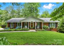 Charming single-story brick home featuring a well-manicured lawn, blooming hydrangeas, and a welcoming front porch at 701 4Th Ne Ave, Conover, NC 28613