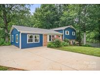 Charming blue home with brick accents, inviting landscaping, and a spacious driveway at 742 Stonecrest Dr, Statesville, NC 28625