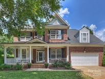Charming two-story brick home featuring a welcoming front porch and well-maintained landscaping with flowering plants at 901 Deercross Ln, Waxhaw, NC 28173