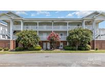 Well-maintained condo building featuring two stories with white railings and mature landscaping at 9271 Meadow Vista Rd, Charlotte, NC 28213