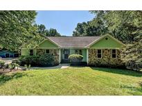 Charming single-story home with stone accents, green siding, and a well-manicured lawn at 14019 Fountain Ln, Charlotte, NC 28278