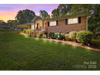 Charming brick home with a well-manicured lawn, front porch, and professionally landscaped front yard at 143 Bostian Lake Rd, Statesville, NC 28677