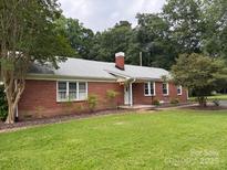 Charming single-story brick home with a well-maintained lawn, surrounded by mature trees and shrubbery at 180 Tower Rd, Troy, NC 27371