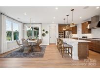 Open-concept kitchen with stainless appliances, island with breakfast bar, and adjacent dining area, perfect for modern living at 327 Ardmore Dr, Belmont, NC 28012