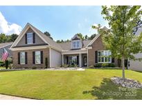 Charming brick home featuring a well-manicured lawn, inviting curb appeal, and decorative stone landscaping at 5129 Devonshire Rd, Denver, NC 28037