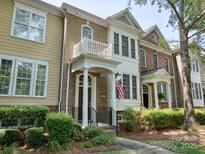 Brick townhouse with a charming balcony, covered porch, manicured landscaping, and American flag at 570 Sixth Baxter Xing # 16, Fort Mill, SC 29708
