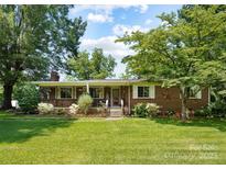 Charming single-story brick home with a well-maintained lawn, mature trees, and a welcoming front porch at 1104 Pump Station Rd, Kannapolis, NC 28081