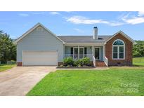 Charming single-Gathering home featuring a two-car garage, brick accents, and a well-maintained front lawn at 142 Family Ln, Mount Holly, NC 28120