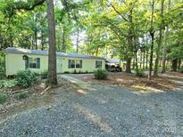 Secluded single story home nestled in a wooded lot with gravel driveway and a covered parking area at 16711 Indian Mound Rd, Albemarle, NC 28001