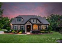 Charming stone and siding home with well-manicured landscaping and a welcoming front entrance at twilight at 2009 Freeport Dr, Indian Trail, NC 28079