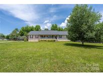 Charming brick home featuring a large front yard and covered porch with white railings at 205 Honey Moss Ln, Salisbury, NC 28146