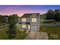 Charming two-story home with gray siding, attached garage, and a cozy front porch with lush landscaping at 2301 Amesbury Ct, Albemarle, NC 28001