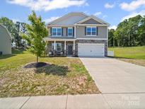 Charming two-story home boasts stone accents, gray siding, well-manicured lawn, and a two car garage at 404 Saddlebred Ln, Locust, NC 28097