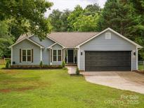 Charming single-story home featuring a well-manicured lawn, gray siding and a two-car garage at 1109 Manchester Ln, Charlotte, NC 28227