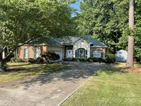 Charming home featuring brick accents, green shutters, and lush, mature landscaping at 1713 Arbor Way, Albemarle, NC 28001