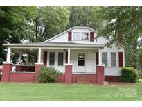 Charming home featuring a covered porch, brick accents, and a well-manicured lawn at 4143 E Maiden Rd, Maiden, NC 28650