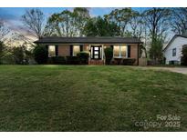 Charming brick ranch-style home with a lush green lawn and mature trees at 4932 Delivau Dr, Charlotte, NC 28215