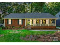 Charming single-story home with a welcoming front porch, brick accents, and lush landscaping at 9334 New Towne Dr, Matthews, NC 28105