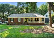 Charming brick and siding home featuring a cozy front porch and well-maintained lawn at 9334 New Towne Dr, Matthews, NC 28105