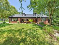 Charming brick home featuring a covered front porch,dormers, and mature trees in a lush green lawn at 112 8Th Nw Ave, Hickory, NC 28601