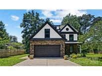 Charming two-story home with stone accents, a black roof, and a well-manicured lawn at 5511 Milhaven Ln, Charlotte, NC 28269
