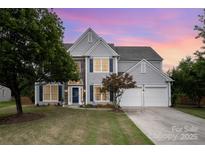 Charming two-story home featuring stone accents, blue shutters, and a well-manicured lawn at twilight at 7623 Rathburn Ln, Charlotte, NC 28277