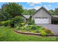 Charming gray home featuring a well-manicured lawn, mature landscaping, and an attached two-car garage at 140 Quiet Cove Rd, Mooresville, NC 28117