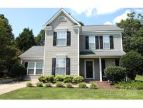 Charming two-story home with gray siding, black shutters and well-maintained landscaping at 148 W Walnut Ave, Mount Holly, NC 28120