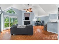 Bright living room with vaulted ceiling, fireplace, hardwood floors, and a large window at 2510 Cranbrook Ln, Charlotte, NC 28207