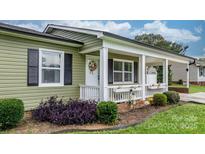 Charming front porch with white railing, columns, and a welcoming wreath on the door, creating a cozy entrance at 3545 Yorkland Dr, Hickory, NC 28601