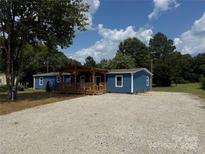 Charming blue home featuring a welcoming, covered front porch and ample gravel parking at 4351 Saluda Rd, Rock Hill, SC 29730