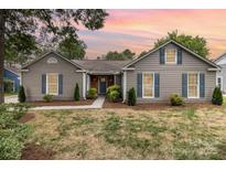 Charming single-story home with gray siding, blue shutters, well-manicured lawn, and inviting walkway at 5234 Bellflower Ln, Charlotte, NC 28227