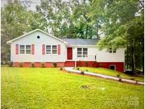 Charming one-story home featuring a cozy front porch and red accents at 7154 Woodcock Trl, Stanley, NC 28164