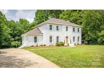 Charming two-story white brick home with a well-manicured lawn and mature trees at 8337 Norcroft Dr, Charlotte, NC 28269