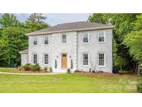 Charming two-story home with a white brick exterior and well-manicured front lawn at 8337 Norcroft Dr, Charlotte, NC 28269