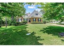 Beautiful two-story home with a stone and siding exterior, lush green lawn, and mature trees at 1036 Foreman Ct, Denver, NC 28037