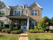 Charming brick two-story home with a welcoming front porch and well-manicured landscaping at 11608 Founders Park Ln, Pineville, NC 28134
