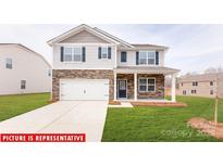 Charming two-story home with a stone facade, attached garage, and well-manicured lawn at 1408 Secrest Commons Dr, Monroe, NC 28112