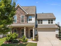 Charming two-story home featuring a stone facade and well-manicured lawn, creating great curb appeal at 15211 Colonial Park Dr, Huntersville, NC 28078