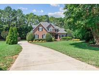 Beautiful brick home featuring a well-manicured lawn and a long driveway at 18800 Boundary Oaks Ct, Davidson, NC 28036