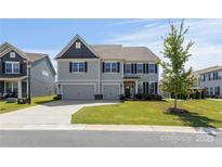 Inviting two-story home with a well-manicured lawn, a two car garage, and classic architectural details at 2097 Saddlebred Dr, Iron Station, NC 28080