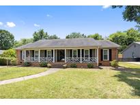 Charming single-story brick home featuring a welcoming front porch with decorative railings and a well-manicured lawn at 5006 Crooked Oak Ln, Charlotte, NC 28226