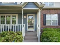 Inviting front porch with blue siding, brick accents, and a glass front door at 9214 Arbourgate Meadows Ln, Charlotte, NC 28277