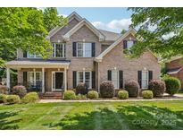Traditional brick home with a manicured lawn and mature landscaping, enhancing its curb appeal at 9735 Devonshire Dr, Huntersville, NC 28078