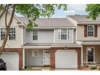 Two-story townhouse with neutral siding, brick accents, and an attached one-car garage at 10613 Prairie Ridge Ln, Charlotte, NC 28213