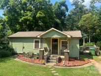Charming green cottage-style home with a cozy front porch and landscaped garden beds at 302 Margarette Ave, Belmont, NC 28012