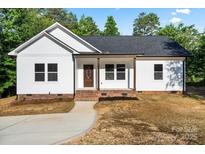 Charming single-story home features a white exterior, brick foundation, and a welcoming front porch at 5328 Oaktree Dr, Gastonia, NC 28052