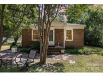 Charming brick home featuring a cozy porch, mature trees, and a well-maintained front yard at 6616 Woodlawn Ln, Indian Trail, NC 28079