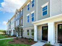 New townhome with light blue vinyl siding, brick accents, manicured lawn, and covered front porch at 11017 Warfield Ave # 4, Huntersville, NC 28078