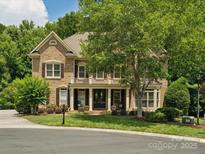 Charming brick home with manicured lawn, covered porch, balcony, and mature landscaping at 2103 Lytton Ln, Matthews, NC 28104